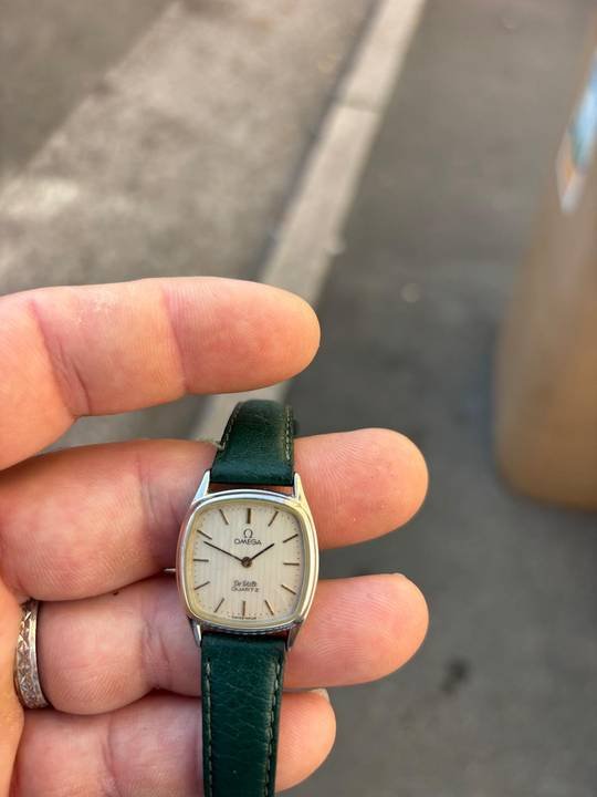 Montre de dame à boîtier coussin et bracelet de cuir vert, tenue dans la main